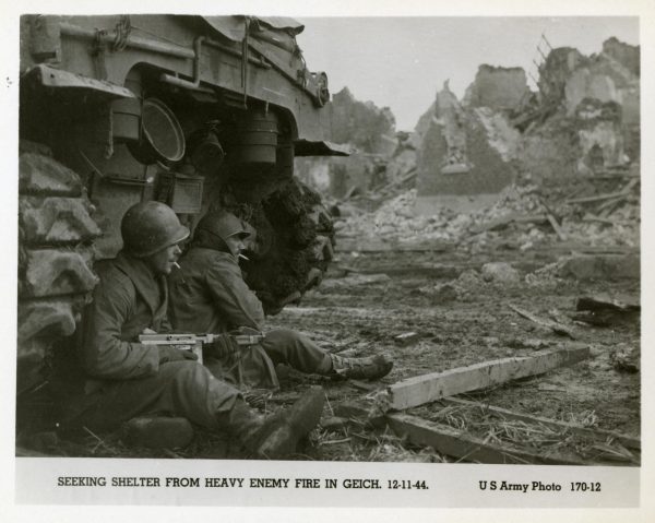 The men of the 3rd Armored Division taking cover behind a tank. Photo provided by Phoebe Feis.